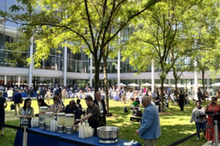 people standing and eating a reception in courtyard of the School of Management 