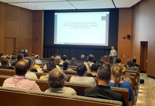 Group sitting in lecture hall with man lecturing