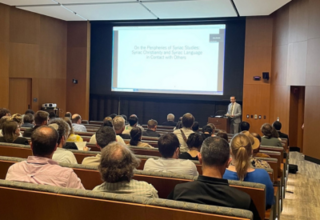 Group sitting in lecture hall with man lecturing 