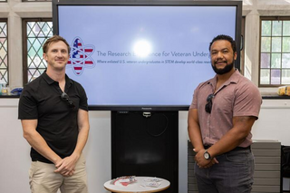 Two presenters in front of screen